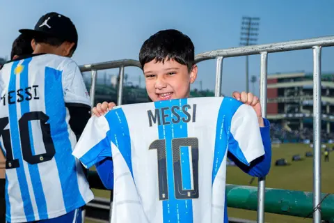 A fan holds a jersey of Messi at the event in Delhi